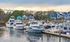 A marina with several yachts docked by colorful houses in the background during a cloudy day.