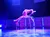 A performer demonstrates impressive flexibility and balance on a chair under vibrant stage lighting.