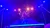 A performer, illuminated by vibrant stage lights, is skillfully balancing on a tightrope in a dramatic, colorful setting.
