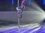A performer in a black and red costume is posing mid-air on a pole under stage lights.