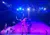 A performer in a pink outfit is skillfully twirling a hula hoop on stage under vibrant, colorful lights.