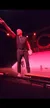 A performer in a stage show is pointing dramatically under red lighting.