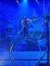 A performer is balancing inside a large rotating wheel on stage with a wintry backdrop.