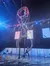 A performer is engaged in a daring acrobatic act inside a giant rotating wheel under blue lighting at a live entertainment event.