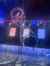 A performer is executing a balancing act on a large spinning wheel on stage, illuminated by colorful stage lighting.