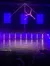 A performer is executing an aerial maneuver on a vertical pole, showcasing flexibility and strength under purple stage lighting in front of an audience.