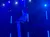 A performer is gracefully suspended in mid-air using aerial silks with a backdrop of blue stage lights.
