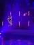 A performer is suspended mid-air during an aerial act on a stage lit with vibrant purple lighting.