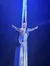 A performer is suspended mid-air, striking a dramatic pose with outstretched arms, wrapped in long fabric from an aerial silk performance, against a starry backdrop.