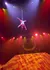 A performer is suspended upside down in mid-air during a colorful aerial act with dramatic lighting effects.