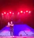 A performer on stage is skillfully demonstrating a strength feat under bright red and purple lights.