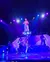 A person is performing on a tall, metallic structure in a stage setting with vibrant lighting effects.
