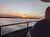 A person is sitting on a boat, watching a vibrant sunset over a calm body of water.