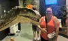 A person is smiling next to a dinosaur exhibit in a museum, with an informational sign in the background.