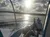 A person relaxes on a boat deck with others in the background, as the sun sets over the water amid scattered clouds.