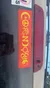 A red bumper sticker with yellow symbols representing various beliefs spells out the word 
