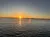 A serene sunset over a calm body of water with a clear sky.