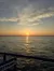A serene sunset over a vast body of water, with soft clouds and a reflective golden pathway on the waves.