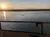 A tranquil sunset over a calm river viewed from behind a railing, with a lone swimmer in the water.