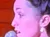 A woman dressed in costume is sitting on a counter holding a microphone in a wood-paneled room with stage lighting.