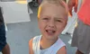A young child on a boat is happily holding a large jellyfish.
