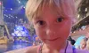 A young girl is showing off a coin or medallion with a pleased expression, standing in front of an indoor venue that resembles a pirate ship stage area.