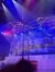 Acrobats perform on a spinning wheel apparatus under colorful stage lights, with a snowy village backdrop.