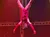 An acrobat dressed in red performs an aerial act while hanging upside down on a dark, starry stage.