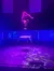 An acrobat is performing a handstand on a raised platform under a purple light, with a backdrop that resembles a starry night.