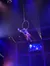 An acrobat is performing on a suspended hoop against a backdrop of colorful lights and a starry stage.