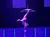 An acrobat performs an impressive one-handed handstand on a high bar, set against a backdrop that mimics a starry night sky.
