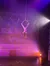 An aerial performer is gracefully suspended upside down in a hoop above a stage with a winter-themed backdrop.