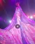 An aerial performer is suspended on a trapeze, with a flowing, illuminated gown cascading down in vibrant pink and purple hues under stage lights.