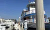 Passengers are boarding a vintage-style paddlewheel boat docked at a pier under a clear blue sky.