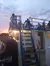 People are gathered on the deck of a boat at sunset, with some sitting on an upper platform accessible by a staircase.