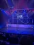 The image depicts a circus performance with two acrobats performing on a large, spinning wheel apparatus under colorful stage lights.