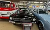 The image shows a black 1966 Ford Mustang displayed between a vintage red vehicle and another car, with a sign detailing its specifications and surrounded by automotive memorabilia on the walls.