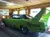 The image shows a bright green 1970 Plymouth Superbird on display indoors, featuring a large rear spoiler and Road Runner graphics.