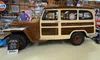 The image shows a vintage 1950 Willys Jeep 2-door station wagon in a museum-like setting, surrounded by automotive memorabilia.