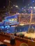 The image shows an indoor theatrical setting with a brightly decorated stage resembling a pirate ship, set against a large pool of water, with an audience seated around the venue, creating an immersive entertainment experience.