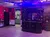 The image shows an interior of a dimly lit bar with a decorative ceiling, a small counter, and signs indicating restrooms.