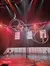 This image captures a vibrant performance with two artists executing acrobatic maneuvers atop rotating circular structures amidst dynamic stage lighting.