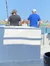 Three individuals, two men and a child, are looking out towards the water on a bright day while on a boat.