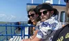 Three people are sitting on a boat, enjoying the sun and the sea breeze, dressed in summer casual wear and sunglasses.