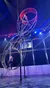 Two acrobats are performing on a large rotating double wheel apparatus under bright stage lights.