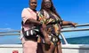 Two people are standing close together on a boat with the ocean and a clear blue sky in the background.