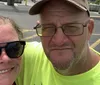Two smiling individuals are taking a selfie in front of the 