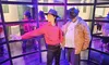 A visitor is posing next to a wax figure that resembles a famous pop star, standing in a distinctive dance pose within an enclosed area with mirrored walls.