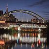 The image features a nighttime cityscape with illuminated bridges spanning a river, which reflects their lights onto the water's surface.