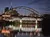 The image depicts a nighttime cityscape featuring brightly lit bridges over a calm river, with a backdrop of illuminated buildings creating reflections on the water.